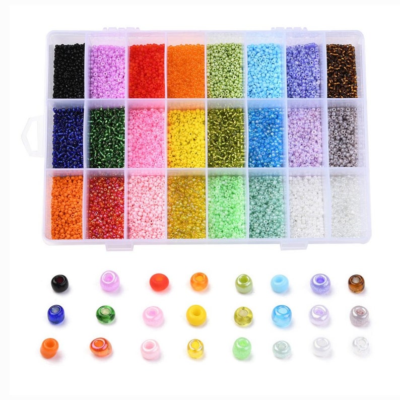 May include: A clear plastic storage box filled with 24 small containers of colorful seed beads. The beads are arranged in rows of different colors, including black, pink, red, orange, green, blue, purple, and white. There are also loose beads scattered on a white surface below the box.