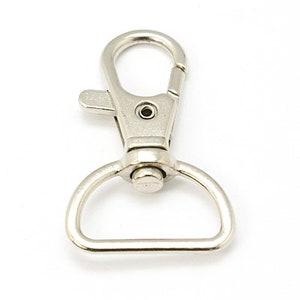 May include: Silver swivel trigger clasp with a D-ring. This metal clasp is commonly used for keychains, lanyards, and other accessories.