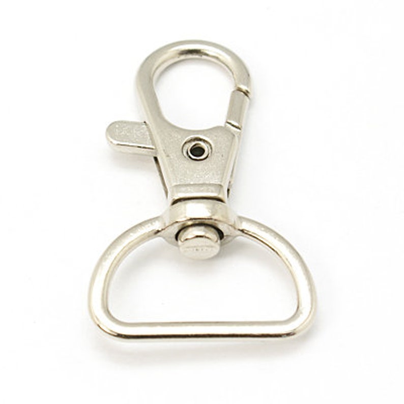 May include: Silver swivel trigger clasp with a D-ring. This metal clasp is commonly used for keychains, lanyards, and other accessories.