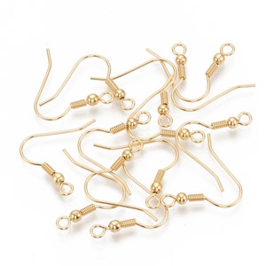 May include: A group of gold-toned earring hooks with a spring-loaded closure and a small ball at the top of the hook.