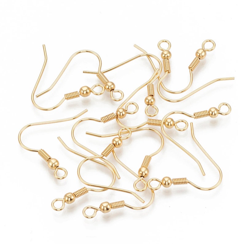May include: A group of gold-toned earring hooks with a spring-loaded closure and a small ball at the top of the hook.