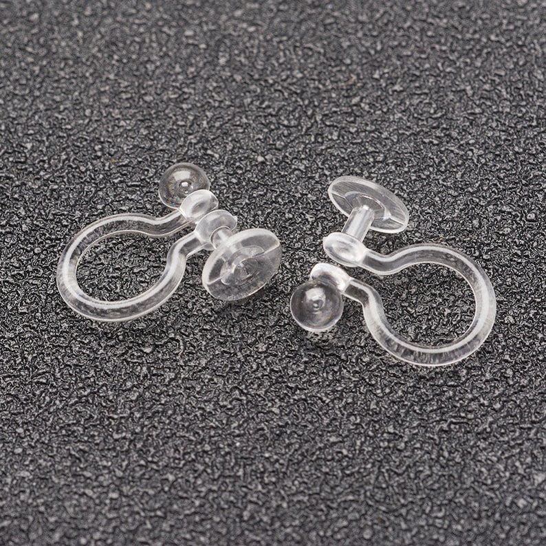 May include: Two clear plastic earring clips. The clips are designed to hold earrings in place without piercing the ear.