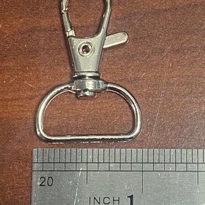 May include: Silver metal swivel clasp with a D-ring, measuring 1 inch in length.