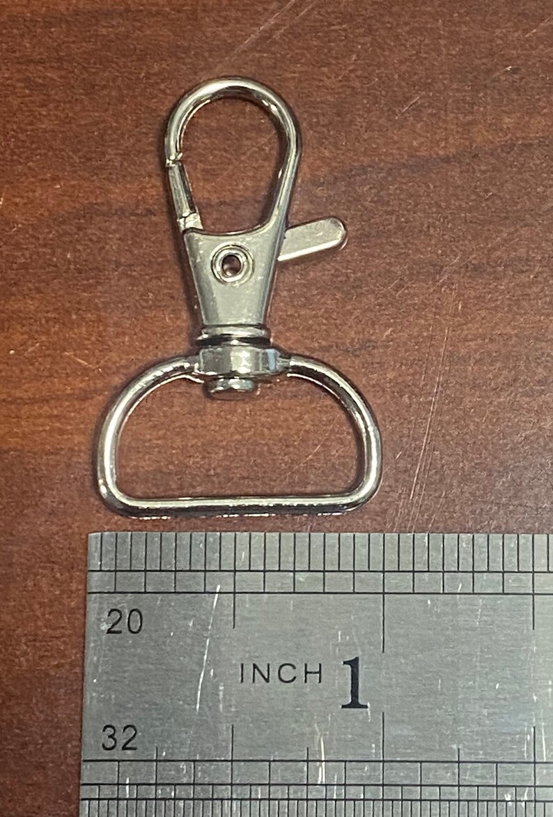 May include: Silver metal swivel clasp with a D-ring, measuring 1 inch in length.