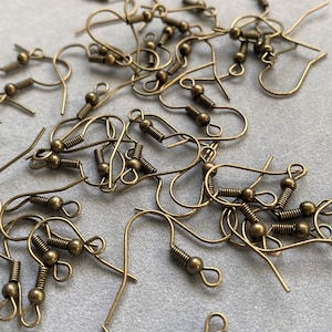 May include: A pile of gold-toned earring hooks with a spring-loaded closure. The hooks are made of metal and have a small ball at the end.