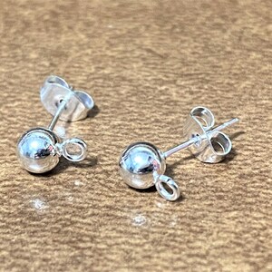 May include: Two silver earring posts with a small ball at the end and a jump ring for attaching a charm.