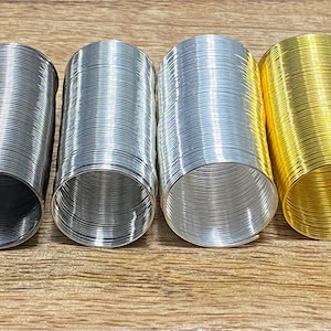 May include: Four metal slinky toys in different colors: black, silver, aluminum, and gold. The slinkies are coiled and ready to be stretched and bounced.