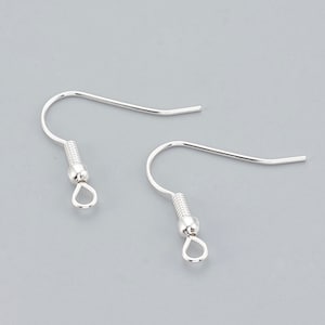 May include: A pair of silver earring hooks with a small loop at the bottom. The hooks are made of metal and have a spring-loaded closure.