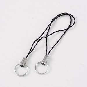 May include: Two black string phone charms with silver metal rings and loops.