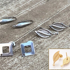May include: A set of silver earring findings, including two leaf shapes, two square shapes, and two teardrop shapes. The leaf shapes have a textured design. The square shapes have a small hole in the center. The teardrop shapes have a loop at the top.