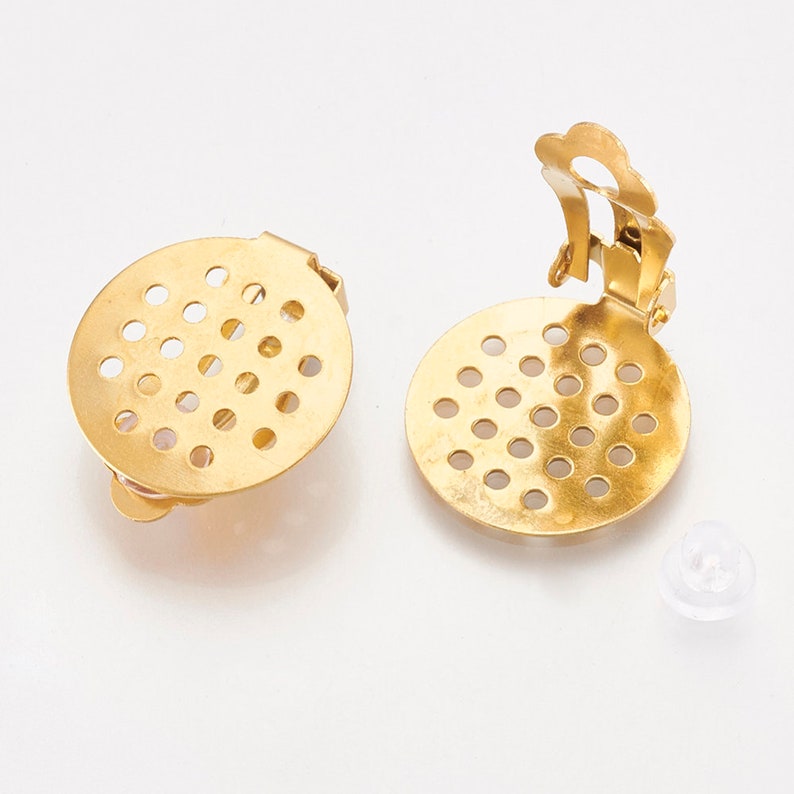 K&ouml;nnte beinhalten: Zwei goldfarbene Ohrringverschl&uuml;sse aus Metall mit einem runden, perforierten Design. Die Verschl&uuml;sse haben einen Clipverschluss.