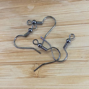 May include: Three silver earring hooks with a small ball at the top of each hook.