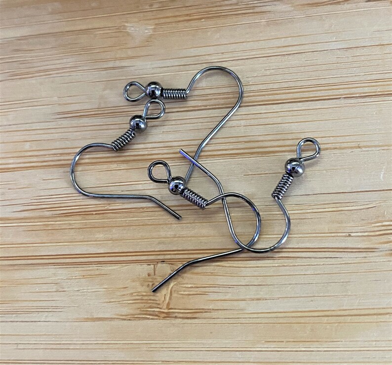 May include: Three silver earring hooks with a small ball at the top of each hook.