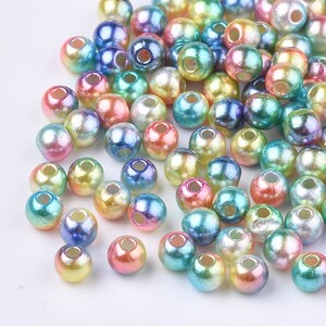 May include: A large assortment of iridescent round beads in various pastel colors, including pink, blue, green, and yellow. The beads have a pearlescent finish and are perfect for jewelry making or crafting.