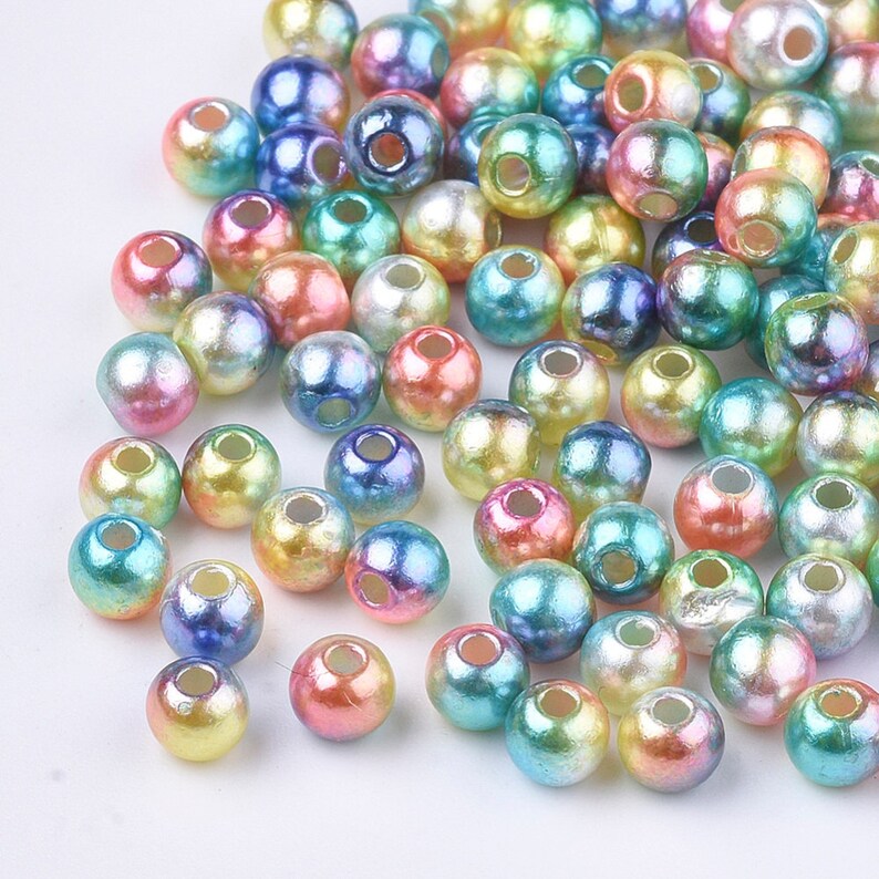 May include: A large assortment of iridescent round beads in various pastel colors, including pink, blue, green, and yellow. The beads have a pearlescent finish and are perfect for jewelry making or crafting.