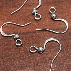 May include: Four silver earring hooks with a small ball at the top of each hook.