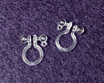 May include: A pair of clear plastic earring backs with small clear plastic balls on each end.