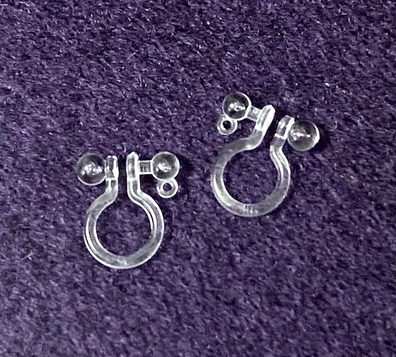 May include: A pair of clear plastic earring backs with small clear plastic balls on each end.