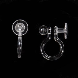 May include: A pair of clear plastic earring backs. One back is a simple, round, flat disc with a small hole in the center. The other back is a more complex design with a small ball on one end and a larger, flat disc on the other end. The back is designed to clip onto the back of an earring.