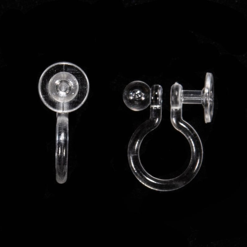 May include: A pair of clear plastic earring backs. One back is a simple, round, flat disc with a small hole in the center. The other back is a more complex design with a small ball on one end and a larger, flat disc on the other end. The back is designed to clip onto the back of an earring.