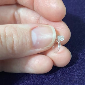 May include: A clear plastic ear cuff with a small, round, clear plastic bead at the top.