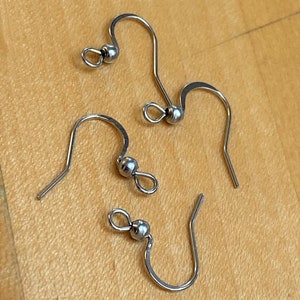 May include: Three silver earring hooks with a small ball at the top of each hook.
