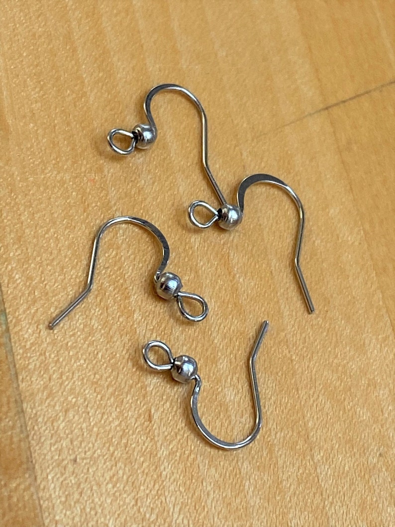 May include: Three silver earring hooks with a small ball at the top of each hook.