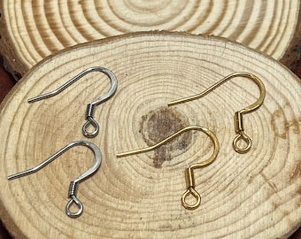 May include: Two pairs of earring hooks, one pair is silver and the other is gold. The hooks are on a wooden surface.