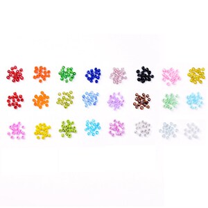 May include: Assortment of 24 small glass seed beads in various colors, including red, orange, yellow, green, blue, purple, pink, brown, black, and white.