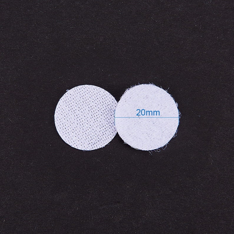 K&ouml;nnte beinhalten: Zwei wei&szlig;e, runde Stoffkreise mit einem Durchmesser von jeweils 20 mm. Die Kreise liegen nebeneinander auf einer schwarzen Oberfl&auml;che.