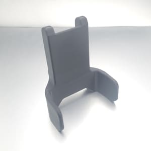 May include: A 3D printed gray plastic phone holder with a curved base and a flat back.