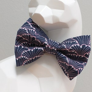 May include: A navy blue bow tie with a pink and white geometric pattern.