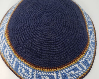 May include: A navy blue knitted kippah with a brown and white patterned trim. The trim features a geometric design.