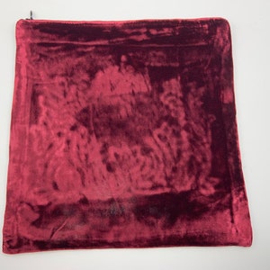 May include: A deep red velvet pillow cover with a zipper closure.