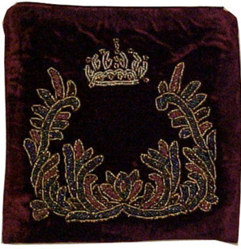May include: A burgundy velvet pillow with a beaded design featuring a crown and floral motifs.
