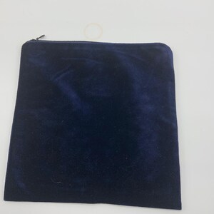 May include: A dark blue velvet zippered pouch. The pouch is made of a soft, plush fabric and has a zipper closure.