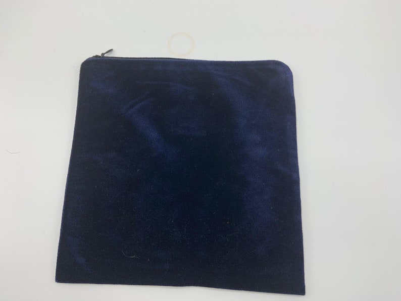 May include: A dark blue velvet zippered pouch. The pouch is made of a soft, plush fabric and has a zipper closure.