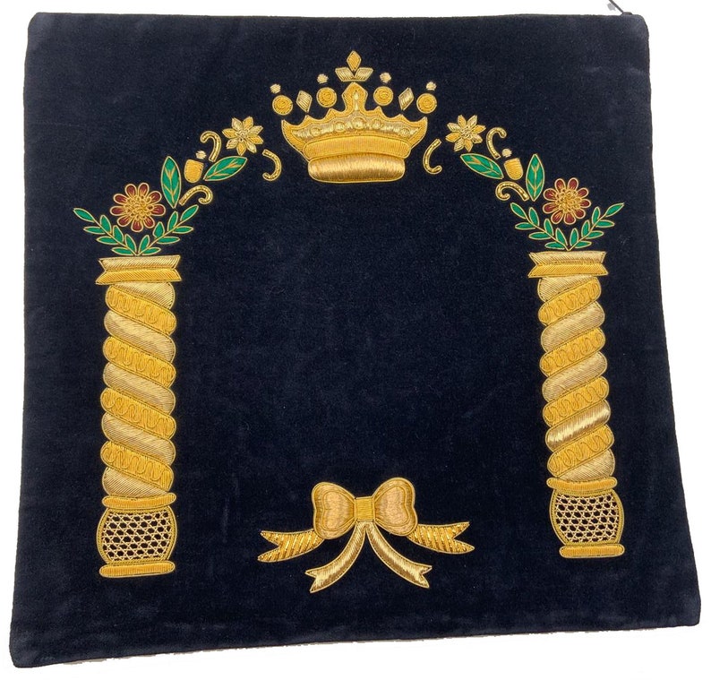 May include: A dark blue velvet prayer shawl with gold embroidery. The embroidery features a crown, two pillars with floral accents, and a bow.