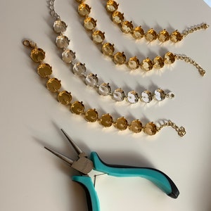 Può includere: Tre catene in metallo dorato e argentato con incastonature rotonde per strass. Nell'immagine è presente anche un paio di pinze turchesi.