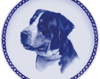 May include: A blue and white porcelain plate with a blue and white image of a Bernese Mountain Dog. The plate has a blue chain border.