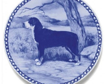 May include: A blue and white ceramic plate with a chain border design. The plate features a black and white illustration of a Bernese Mountain Dog standing in a field.