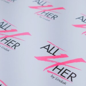May include: Multiple white sheets of paper with the phrase "ALL HER by Lindak" printed in black and pink. The pink is in a stylized, brushstroke font.