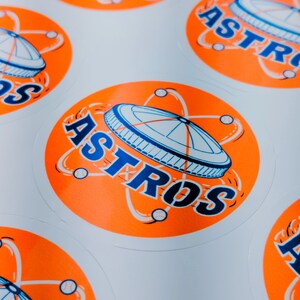 May include: Orange and blue round stickers with the word "ASTROS" and a stylized image of a baseball stadium.