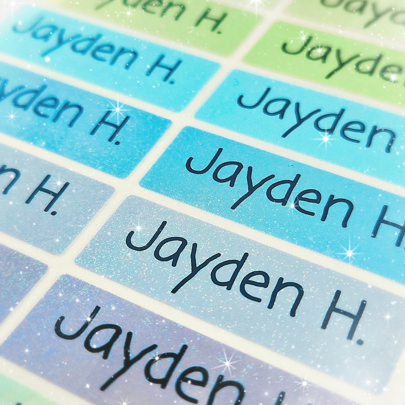 May include: A close-up of a set of colourful, glittery name labels with the name "Jayden H." printed on each label.