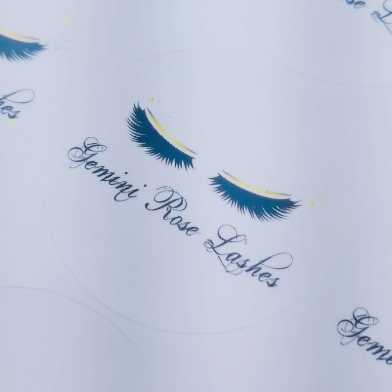 May include: White sticker with a black and gold eyelash design and the text "Gemini Rose Lashes".