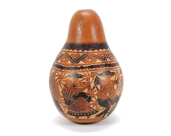May include: A brown gourd with a black and brown geometric design and a scene of people dancing. The gourd is carved with intricate details.