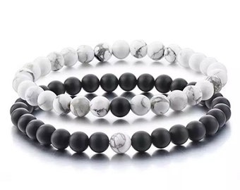 Puede incluir: Dos pulseras de cuentas, una negra y otra blanca, con un diseño de yin yang. Las pulseras están hechas de cuentas pequeñas y redondas.