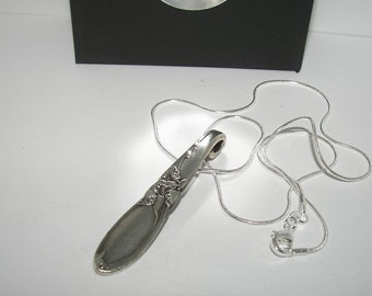 May include: A silver spoon necklace with a delicate floral design. The spoon is attached to a silver chain with a lobster clasp.