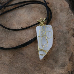 May include: A white, translucent stone pendant wrapped in gold wire, hanging from a black cord.