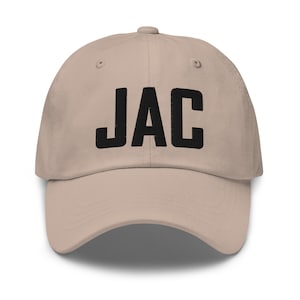 May include: A beige baseball cap with the word "JAC" embroidered in black on the front.